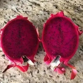 Freshly cut red-fleshed dragon fruit halves on a granite countertop
